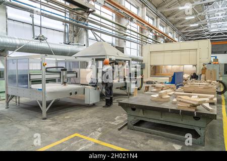 Operaio di intagliatrice automatica in fabbrica di legno. Produzione professionale di carpenteria industriale. Foto Stock