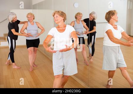 Le donne anziane che esercitano la danza balletto si muove con il formatore Foto Stock