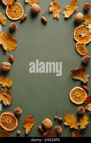 Telaio fatto di arance, foglie di quercia secca, noci, ghiande su fondo verde di vintgae. Autunno autunno, concetto di Thanksgiving. Foto Stock