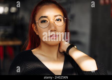 Ritratto di una donna asiatica sorridente che indossa occhiali, bella donna coreana che posa guardando la macchina fotografica in posa per la foto Foto Stock