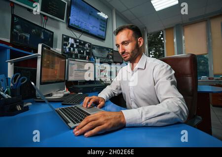 Amministratore server maschio che gestisce il data center dalla sala di controllo Foto Stock
