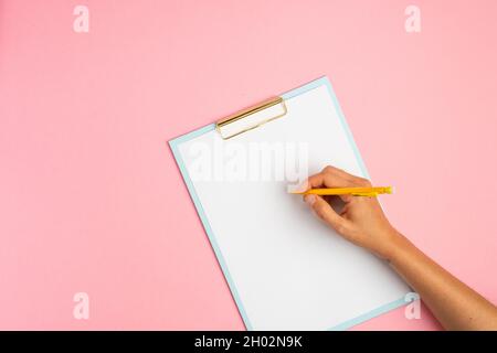 Area di lavoro rosa con lavagna a clip vuota e matita Foto Stock