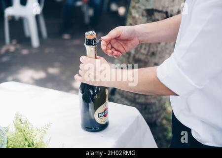 NORALA, PH– 22 SETTEMBRE 2021: Mani che aprono la bottiglia di vino frizzante Martini su un tavolo bianco. Messa a fuoco selettiva. Spazio di copia. Foto Stock