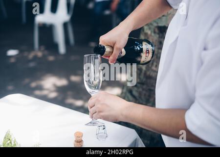 NORALA, PH– 22 SETTEMBRE 2021: Primo piano di mani versare la bottiglia di vino frizzante Martini in un alto vitigno. Messa a fuoco selettiva. Spazio di copia. Foto Stock