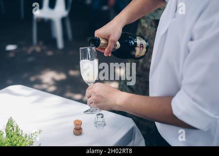 NORALA, PH– 22 SETTEMBRE 2021: Primo piano di mani versare la bottiglia di vino frizzante Martini in un alto vitigno. Messa a fuoco selettiva. Spazio di copia. Foto Stock