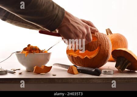 Dettaglio di uomo che intagliano e svuotano una zucca per la festa di Halloween. Vista frontale. Composizione orizzontale. Foto Stock