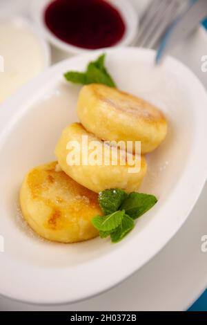 Una porzione di tre pancake rotondi di formaggio cagliato su un piatto bianco. Colazione sana. Sfondo alimentare. Spazio di copia. Foto Stock