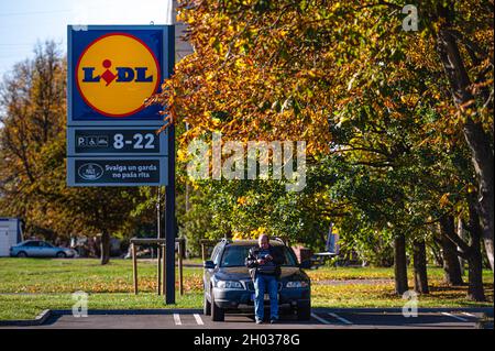 Riga, Lettonia, 9 ottobre 2021: Stand con logo della catena di supermercati LIDL e orari di apertura del negozio presso il parcheggio del negozio Foto Stock