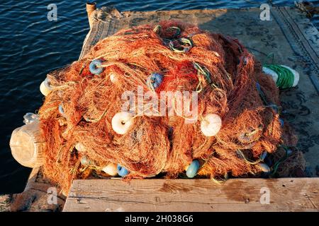 Palo di rete da pesca industriale con boa sul bacino di legno. Foto Stock