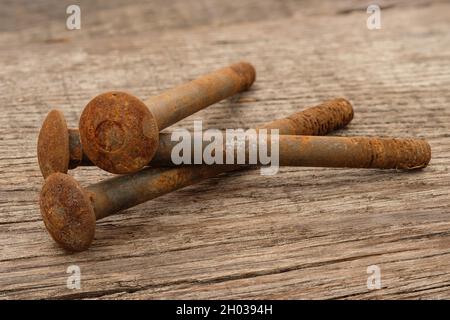 Primo piano di viti di metallo arrugginite pila su un legno rustico Foto Stock