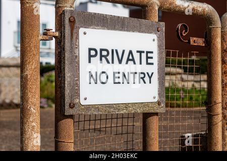 Un cartello privato senza ingresso su un vecchio cancello di metallo arrugginito Foto Stock