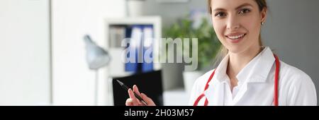 Ritratto di sorridente dottore con penna a sfera e stetoscopio sul collo Foto Stock