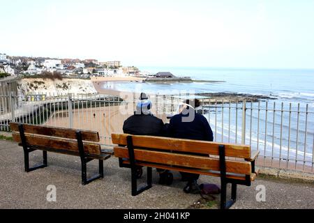 coppia seduta, vista della baia vichinga sulla spiaggia di broadstairs, isola di thanet, kent orientale, uk marzo 2021 Foto Stock