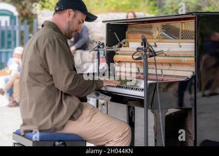 Il pianista e compositore contemporaneo Elliott Jacqués suona il pianoforte sulla spiaggia di Trebah Garden a Polgwidden Cove in Cornovaglia. Foto Stock