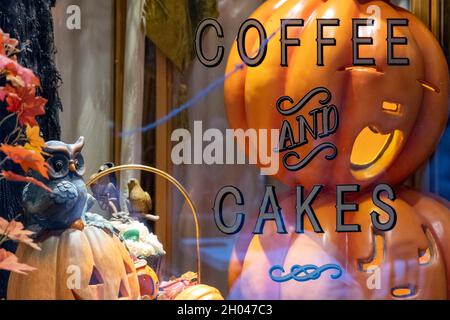 Decorazione di Halloween. Caffè e torte. Riflessi sulla finestra di un negozio di alimentari. Fuori per lo shopping di festa. Oggetti decorativi festosi e ornamenti di zucca Foto Stock