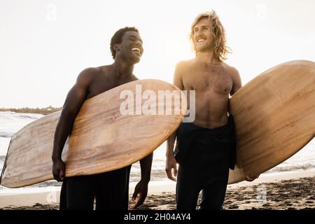 Giovani e diversi surfisti che si divertono sulla spiaggia dopo una sessione di surf - persone che praticano sport acquatici estremi Foto Stock