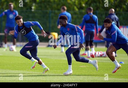 Jadon Sancho, Bukayo Saka e Tyrone Mings (sinistra-destra) in Inghilterra durante una sessione di allenamento presso Hotspur Way Training Ground, Londra. Data foto: Lunedì 11 ottobre 2021. Foto Stock