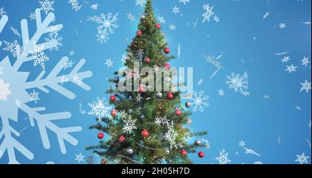 Immagine di fiocchi di neve cadenti sopra l'albero di natale Foto Stock