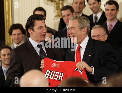 In questa foto di archivio, Carolina Hurricanes capitano Rod Brind'Amour, a sinistra, presenta il presidente George Bush con un maglione Hurricanes con il nome del presidente su di esso durante una cerimonia tenuta nella stanza Est della Casa Bianca a Washington, DC, venerdì 2 febbraio 2007. Il presidente si è complimentato con la squadra per il campionato NHL Stanley Cup nel giugno 2006. (Foto di Chris Seward/Raleigh News & Observer/TNS/Sipa USA) Foto Stock