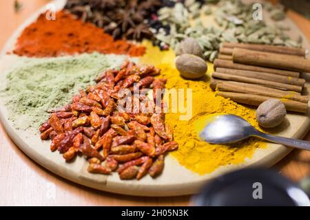 Mix di spezie diverse disposte su piatto di legno Foto Stock