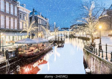 Antica vista sul canale olandese Oude Rijn con ponte, edifici storici e luci natalizie nel centro di Leiden, Paesi Bassi Foto Stock