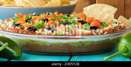 Una vista stretta di un tuffo fatto in casa a 7 strati con un chip di tortilla che attacca fuori. Foto Stock