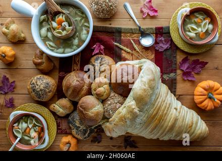 Vista dall'alto in basso delle ciotole della zuppa di tacchino con una cornucopia di pane riempita con i rotoli. Foto Stock