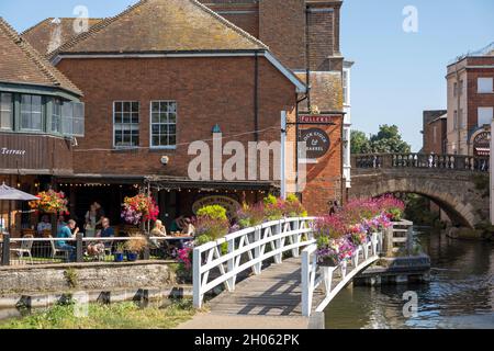 Newbury, Berkshire, Inghilterra, Regno Unito. 2021. Paesaggio verso il ponte della città vecchia e un pub con esposizione floreale lungo il canale Kennett e Avon Foto Stock