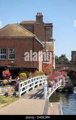 Newbury, Berkshire, Inghilterra, Regno Unito. 2021. Paesaggio verso il ponte della città vecchia e un pub con esposizione floreale lungo il canale Kennett e Avon Foto Stock