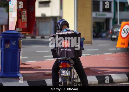 Un pilota di consegna McDonald in attesa sulla motocicletta sul lato della strada della città. Foto Stock