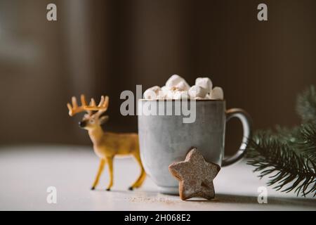 Cioccolata calda con marshmallows in un'atmosfera natalizia con pan di zenzero. Foto atmosferica, sul tavolo una tazza con cacao, biscotti di pan di zenzero e CHRI Foto Stock