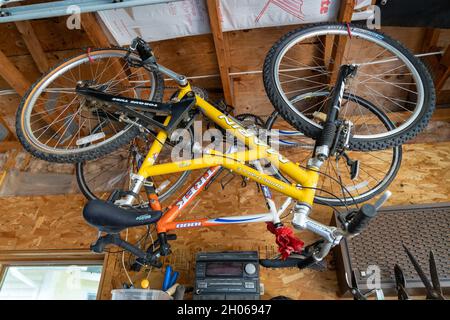 Scandia, Minnesota - 29 settembre 2021: Due biciclette appese al soffitto in un garage, per rimessaggio invernale Foto Stock