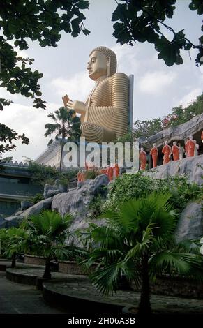 SRI LANKA il Buddha d'Oro all'ingresso delle grotte del Tempio d'Oro di Dambulla che ha molte statue di Buddha all'interno Foto Stock