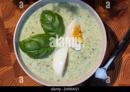 Helsinki / Finlandia - 10 OTTOBRE 2021: Cucina tradizionale finlandese; primo piano di un piatto di zuppa di spinaci con uova sode e condimento con basilico Foto Stock