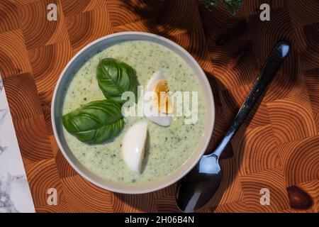 Helsinki / Finlandia - 10 OTTOBRE 2021: Cucina tradizionale finlandese; primo piano di un piatto di zuppa di spinaci con uova sode e condimento con basilico Foto Stock