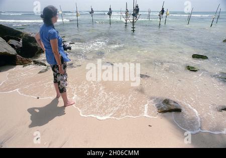 SRI LANKA: I pescatori di Tangalle sospesi sul mare nel modo in cui fanno la loro tecnica tradizionale per catturare il pesce su pali Foto Stock