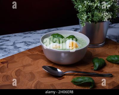 Helsinki / Finlandia - 10 OTTOBRE 2021: Cucina tradizionale finlandese; primo piano di un piatto di zuppa di spinaci con uova sode e condimento con basilico Foto Stock