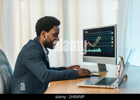 Broker nero maschile utilizzando il computer e il commercio online Foto Stock