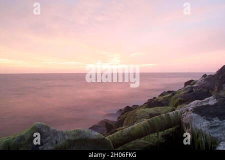 Lunga esposizione durante il tramonto con rocce di muschio in primo piano Foto Stock