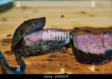 Fuoco selettivo di un filetto di manzo affettato in grasso su una superficie di legno Foto Stock