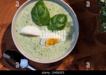 Helsinki / Finlandia - 10 OTTOBRE 2021: Cucina tradizionale finlandese; primo piano di un piatto di zuppa di spinaci con uova sode e condimento con basilico Foto Stock