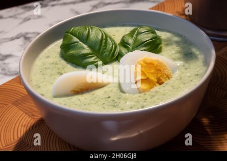 Helsinki / Finlandia - 10 OTTOBRE 2021: Cucina tradizionale finlandese; primo piano di un piatto di zuppa di spinaci con uova sode e condimento con basilico Foto Stock