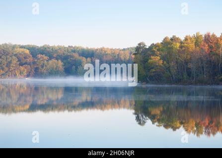 Alberi di colore autunnale su un lago confuso e calmo nel nord del Minnesota all'alba Foto Stock