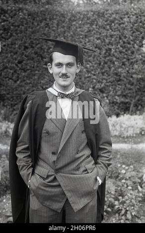 Anni '50, storico, un giovane inglese con un baffo corto e indossando un abito a doppia prora e una cravatta ad arco in posa per la sua foto in un abito da laurea e cappellino accademico quadrato, spesso definito come cappellino e abito, Inghilterra, Regno Unito. Indossato con regalia accademica alle cerimonie di laurea, il suo tipo speciale di cappellino è noto come un mortarboard o a volte come cappellino Oxford e consiste di una tavola quadrata orizzontale fissata su un cappellino cranio con un tasello attaccato al centro. Il suo aspetto distintivo significa che la PAC è associata al mondo accademico. Foto Stock