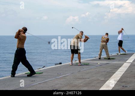 Oceano Indiano, Stati Uniti. 9 ottobre 2021. I marinai della Marina degli Stati Uniti colpiscono le palle da golf in mare durante un picnic in acciaio sulla piattaforma di volo del vettore aereo di classe Nimitz USS Carl Vinson sulla strada per unirsi a Exercise Malabar 9 ottobre 2021 nell'Oceano Indiano. Credit: MCS Emily Claire Bennett/U.S. Navy/Alamy Live News Foto Stock