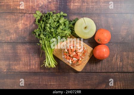 Pico de gallo su un tagliere circondato da ingredienti freschi. Foto Stock