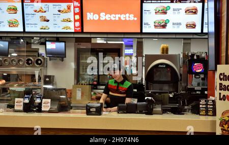Giovane e attraente personale femminile che lavora dietro il bancone nel fast food Burger King, Regno Unito Foto Stock