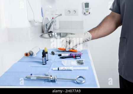 Foto in crosta di una persona che prende uno strumento da un tavolo con strumenti sterili per una clinica dentale Foto Stock