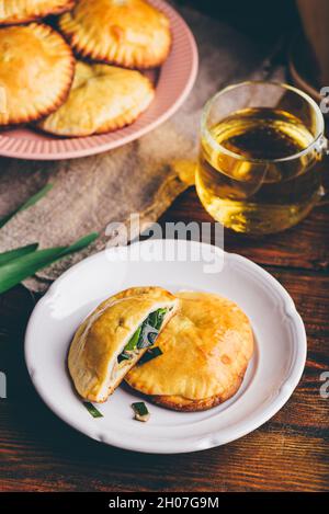 Dolci al forno ripieni di erba cipollina siberiana e funghi su piatto bianco Foto Stock