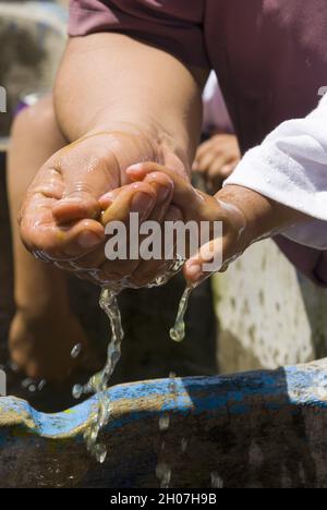 Mani dei bambini latini che dipingono e bevono acqua, celebrazione educativa. Foto Stock